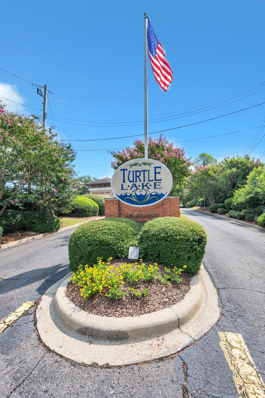 a sign for turtle creek apartments with an flag in front of the street